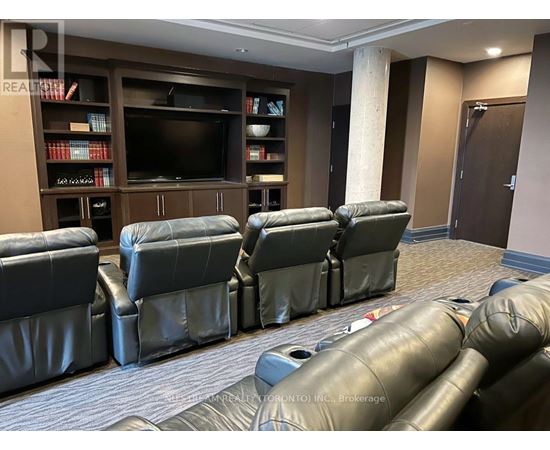 A living room with a row of black leather chairs facing a television.