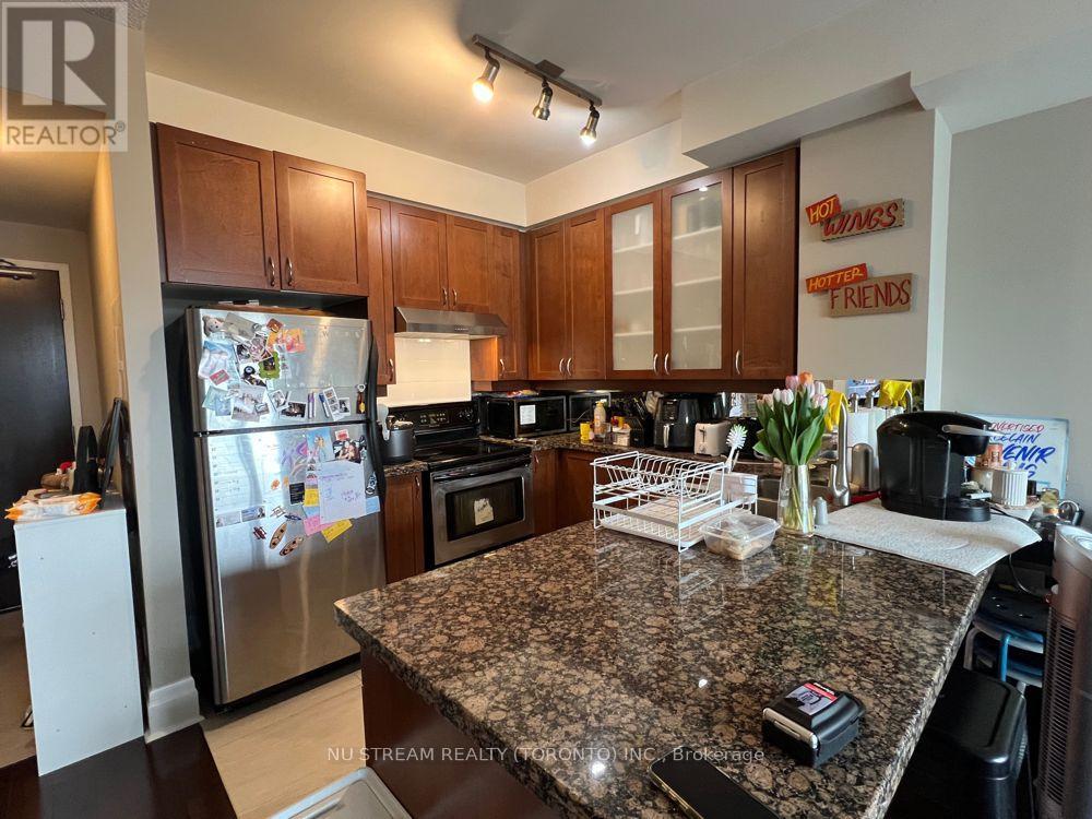 A kitchen with granite countertops and a refrigerator with magnets on it.