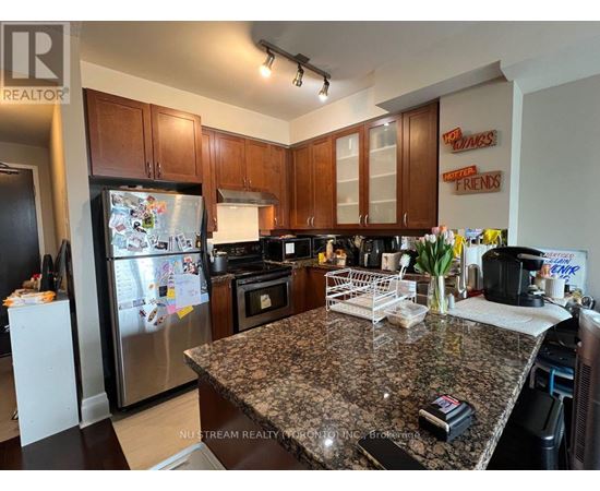 A kitchen with granite countertops and a refrigerator with magnets on it.