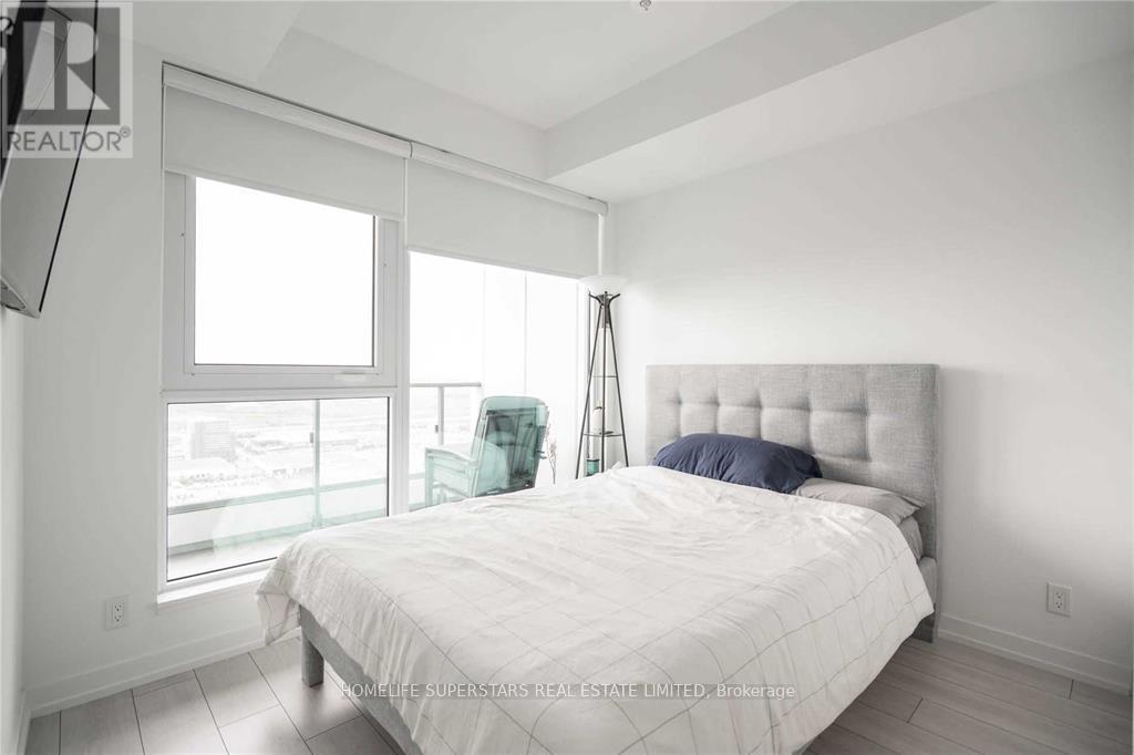 A bedroom with a large bed and a window overlooking the balcony.