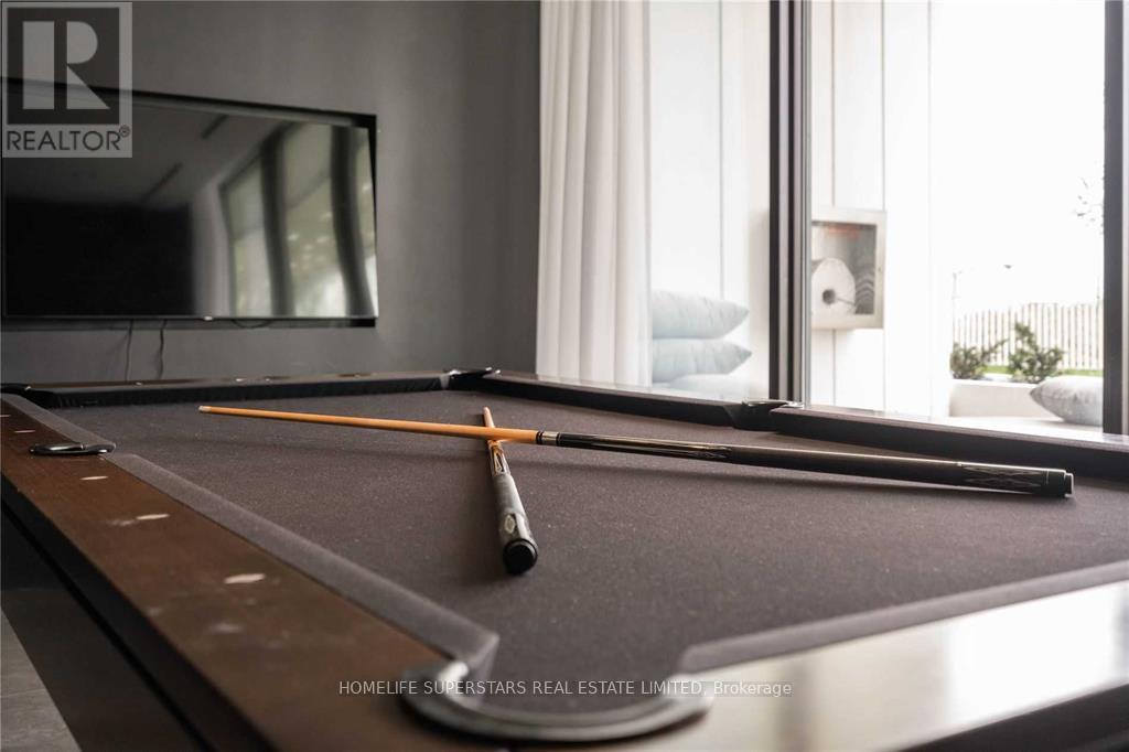 A pool table with a cue stick and ball chalk in the foreground.