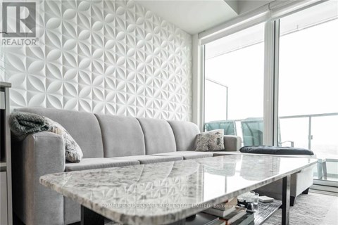 A modern living room with a grey sofa and a glass table.