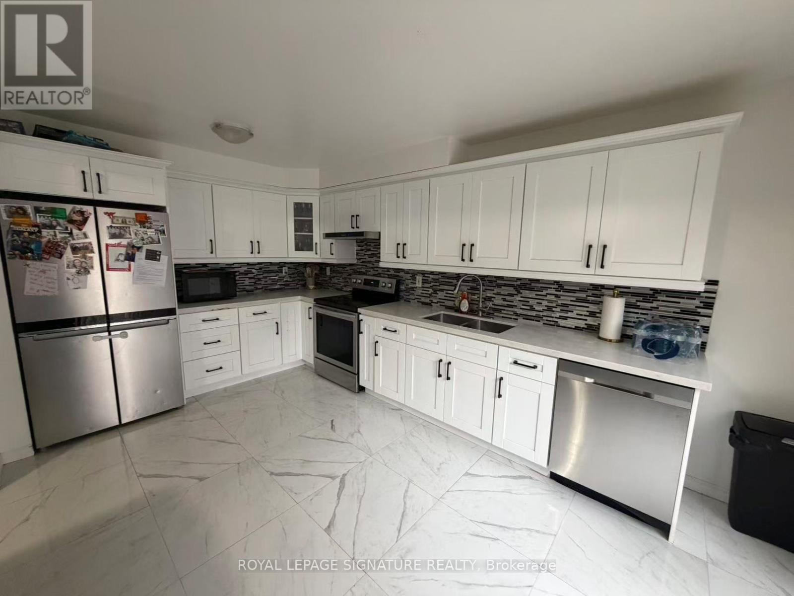 A kitchen with white cabinets and a black fridge.