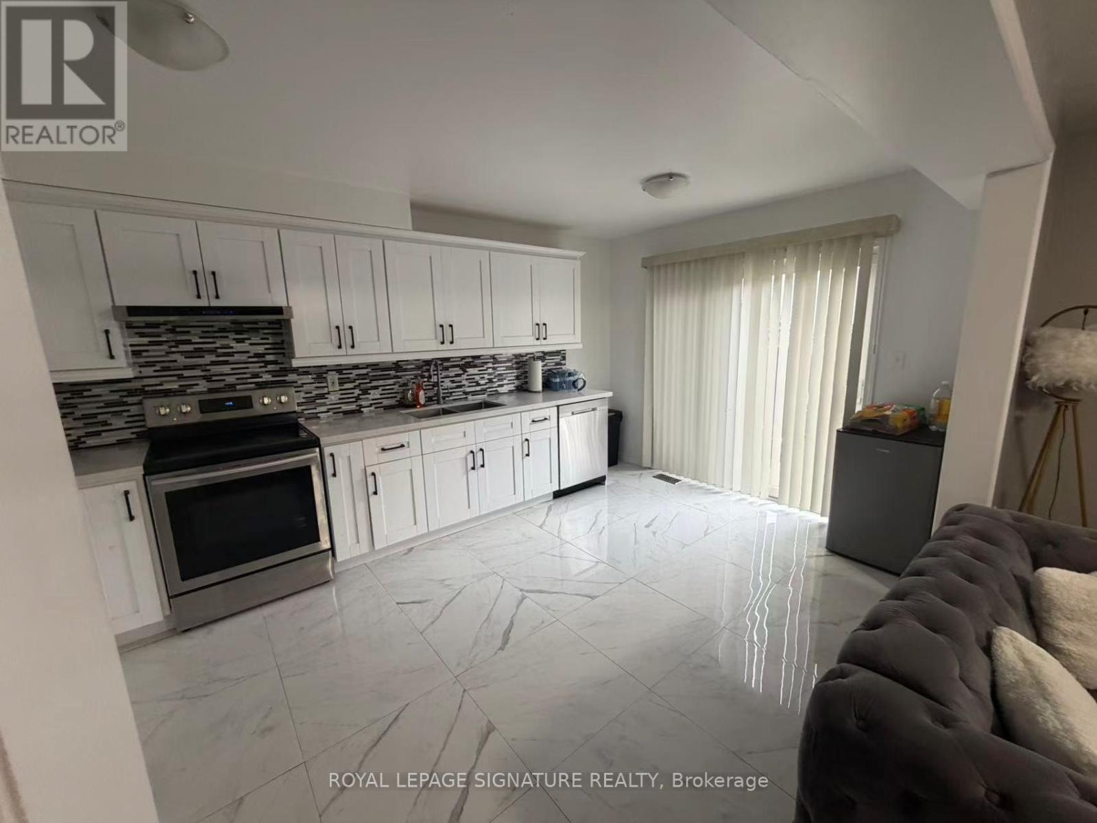 A kitchen with white cabinets and a stone backsplash.
