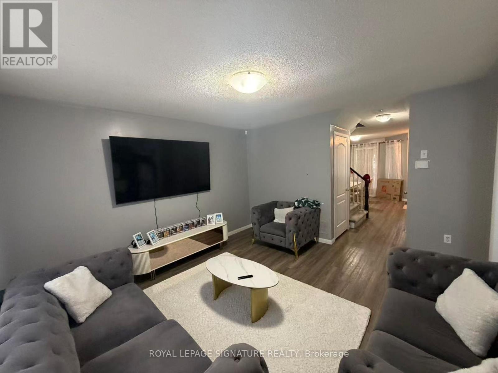 A living room with a grey couch and a flat screen TV mounted on the wall.