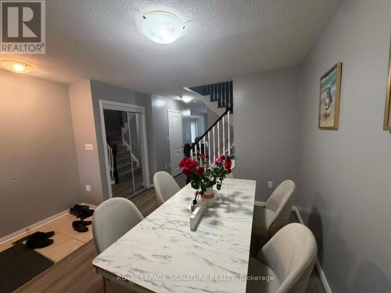 A dining room with a table and chairs and a painting on the wall.
