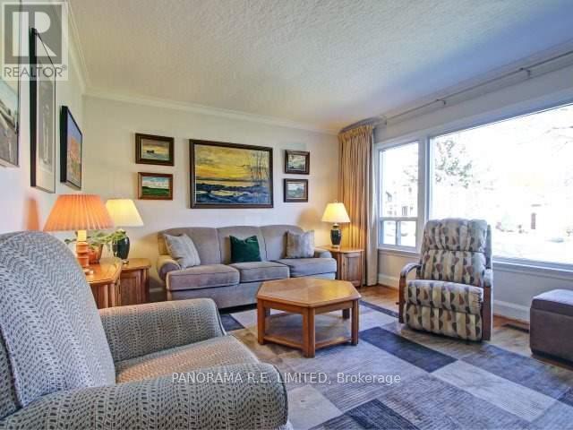 A living room with a grey couch, a wooden coffee table, and a large window with curtains.