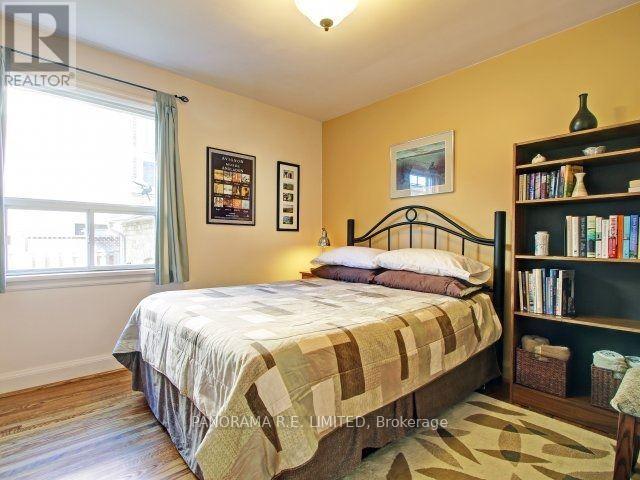 A bedroom with a bed, a bookshelf, and a window.