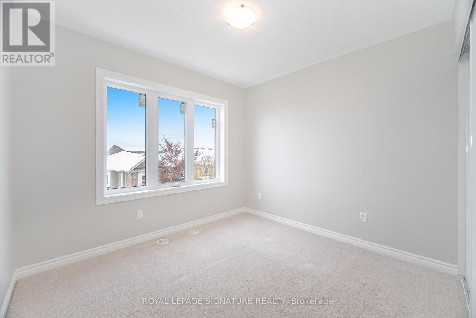 A white room with a window showing a house and trees outside.