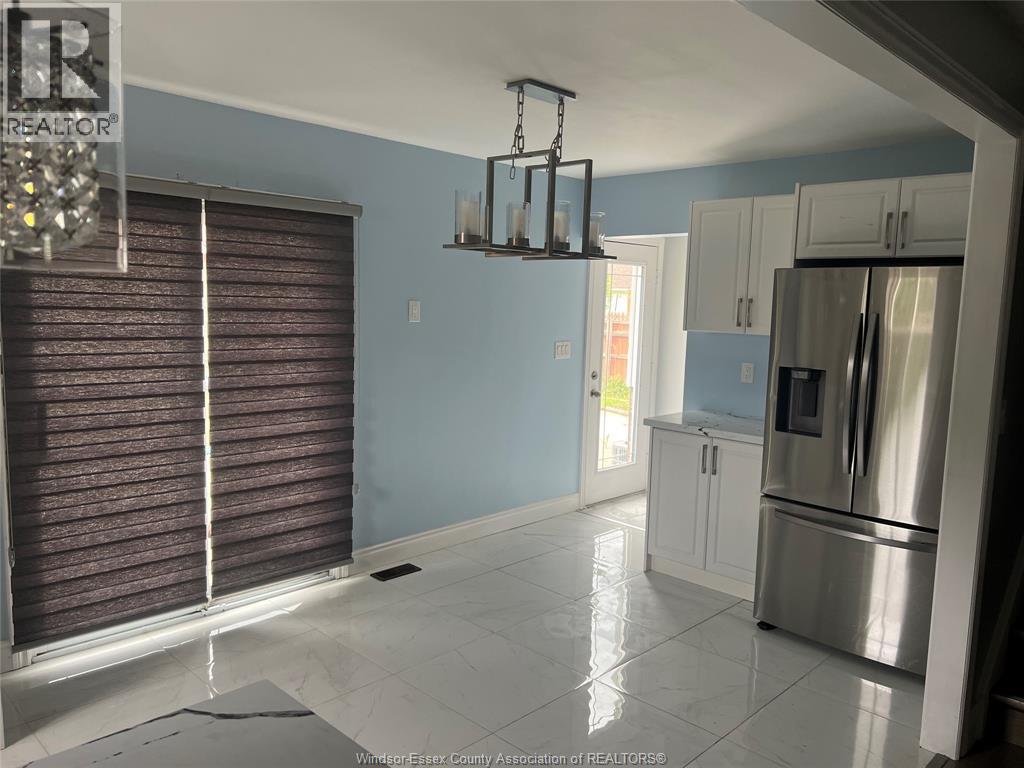 A kitchen with a stainless steel refrigerator and white cabinets.