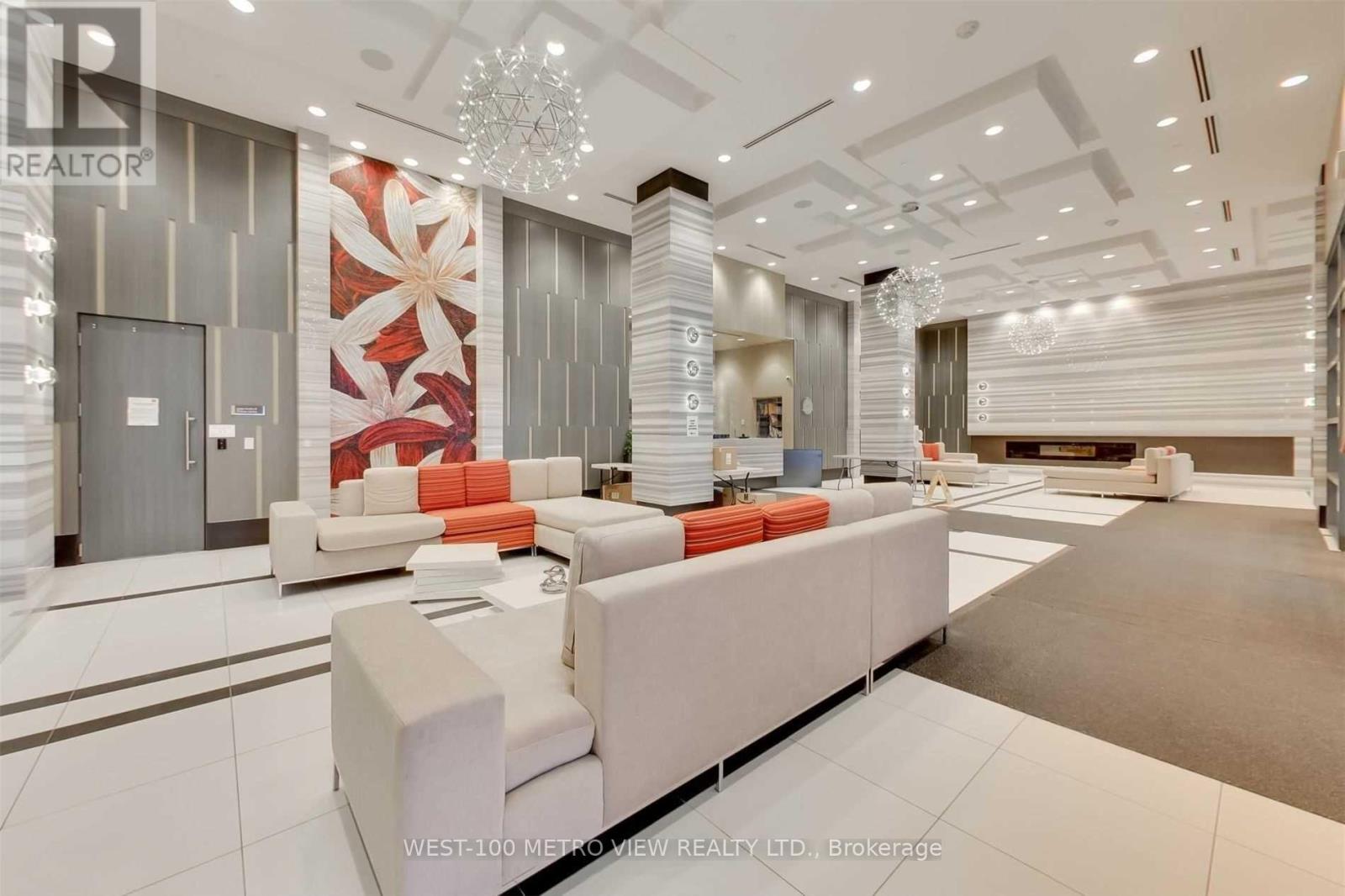 A white sofa with orange pillows is in the middle of a spacious room.