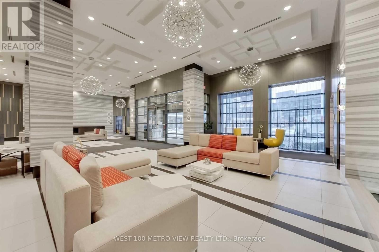 A well-lit, modern living room with a large sofa set and a chandelier.