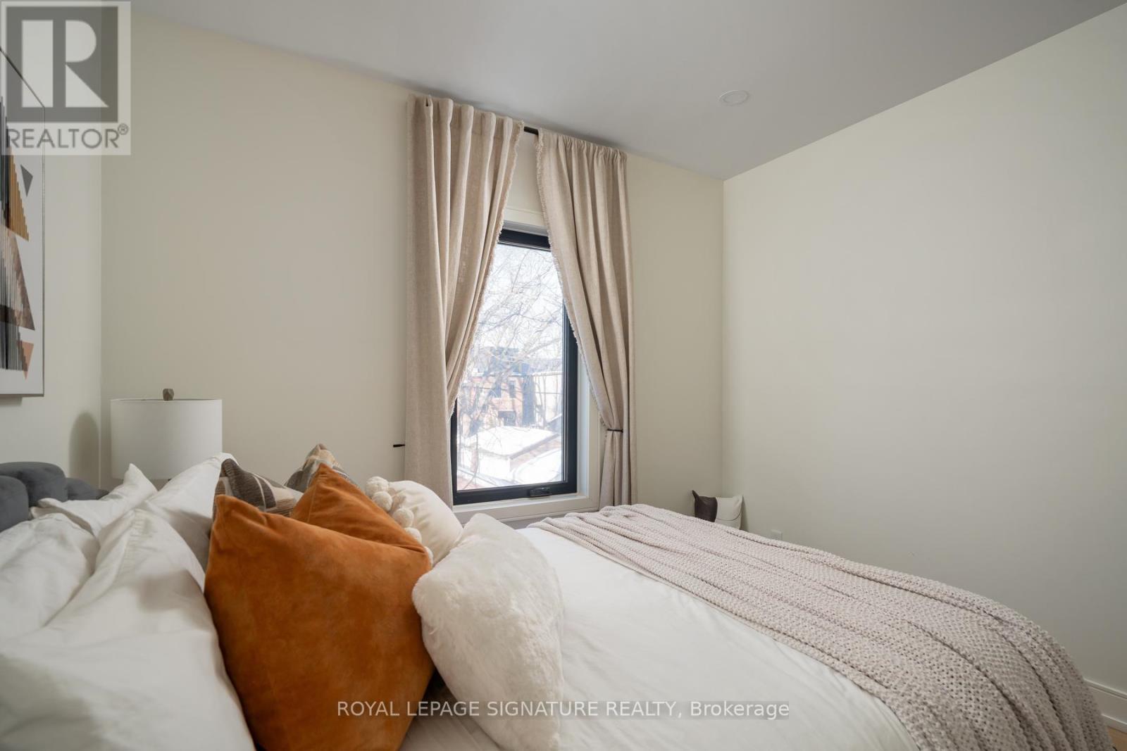 A bedroom with a large bed and a window with curtains.
