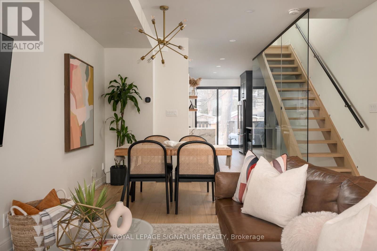 A living room with a brown couch and a glass staircase.