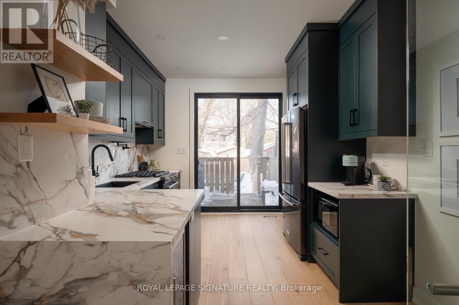 A modern kitchen with dark cabinets and a marble countertop.