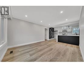 A spacious room with wooden flooring and white walls.