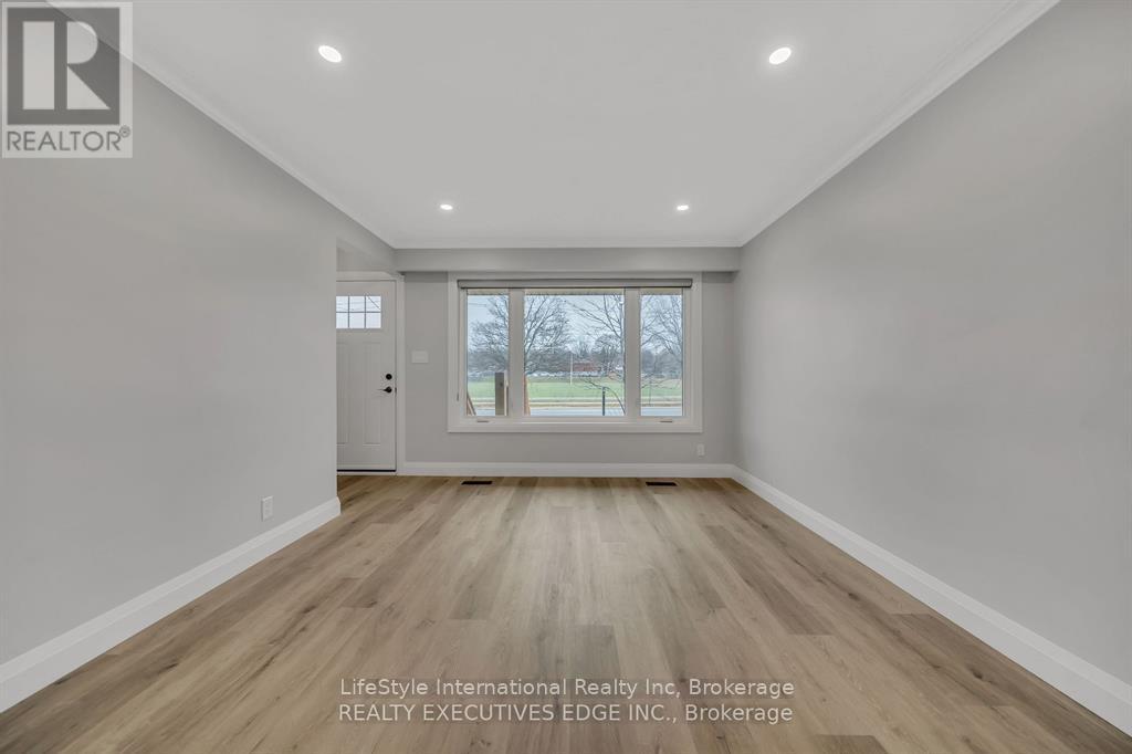 A spacious room with wooden flooring and a large window.