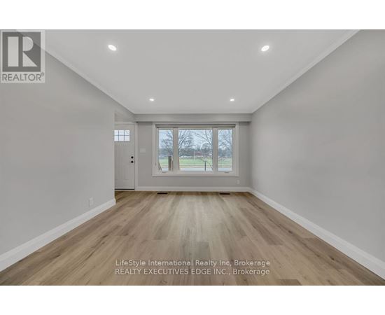 A spacious room with wooden flooring and a large window.
