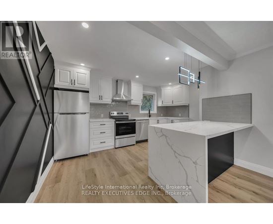 A modern kitchen with a white marble island and wooden flooring.