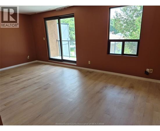 A room with wooden flooring and a large window.