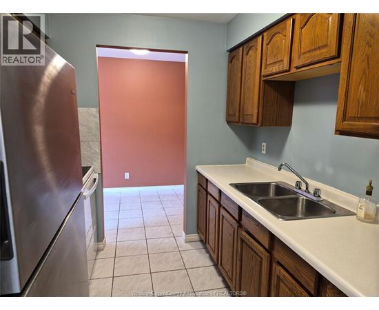 A kitchen with a sink, refrigerator, and cabinets.