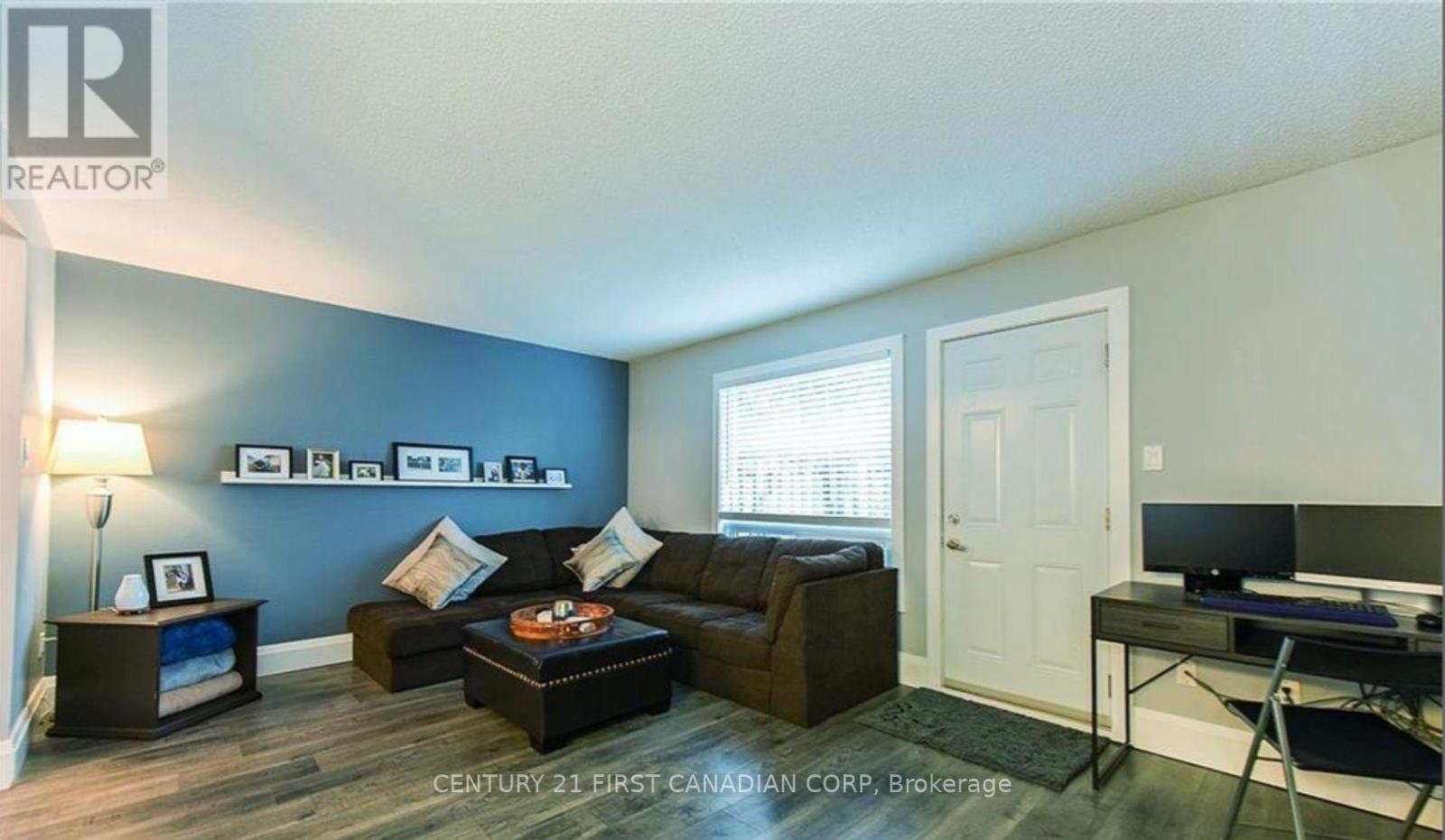 A living room with a brown couch and a blue wall.