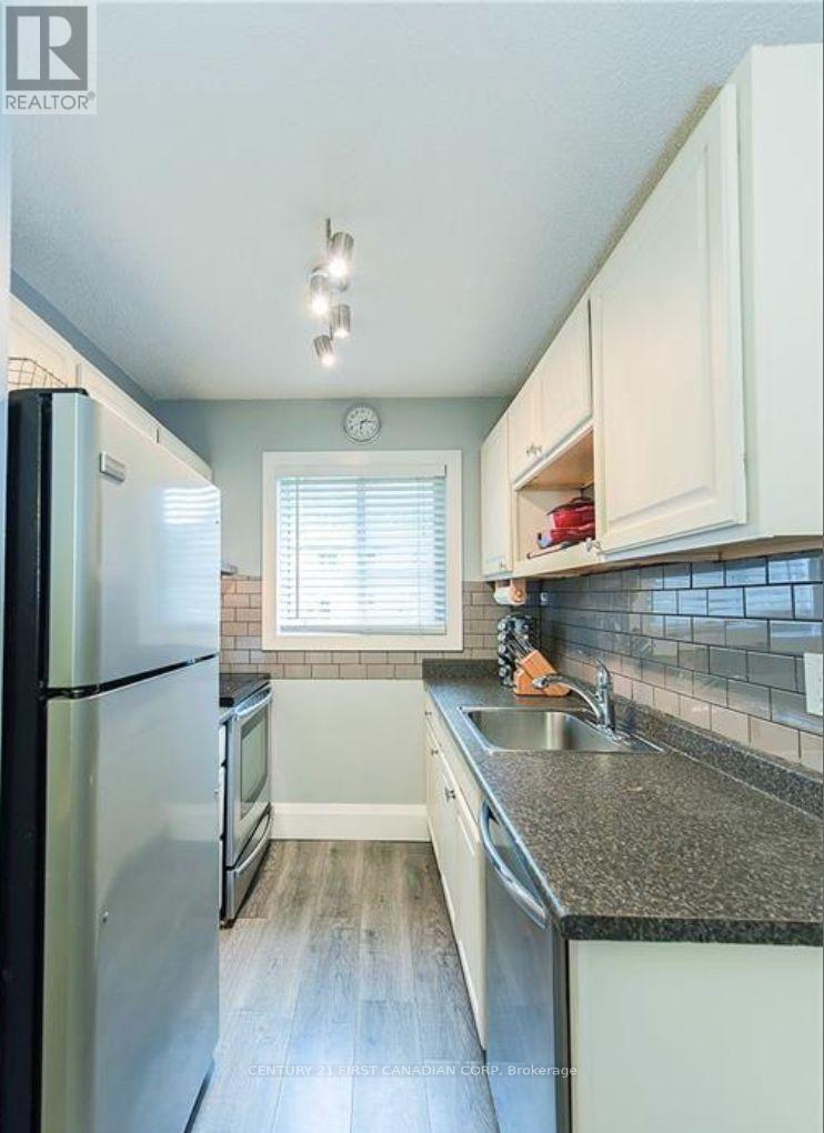A kitchen with a refrigerator, sink, and cabinets.
