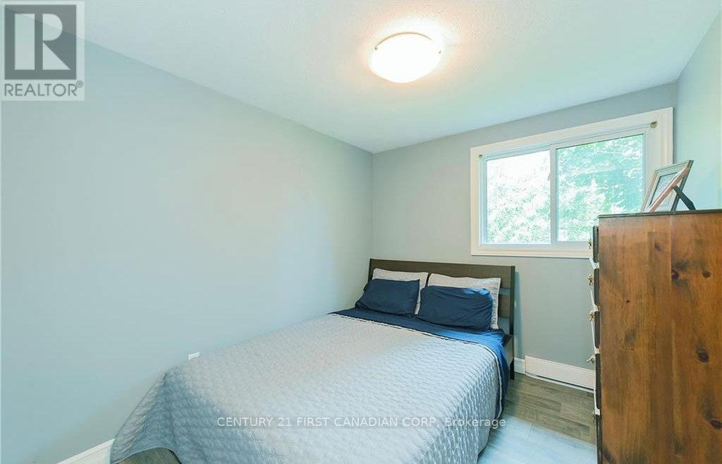 A bedroom with a bed, a window, and a wooden dresser.