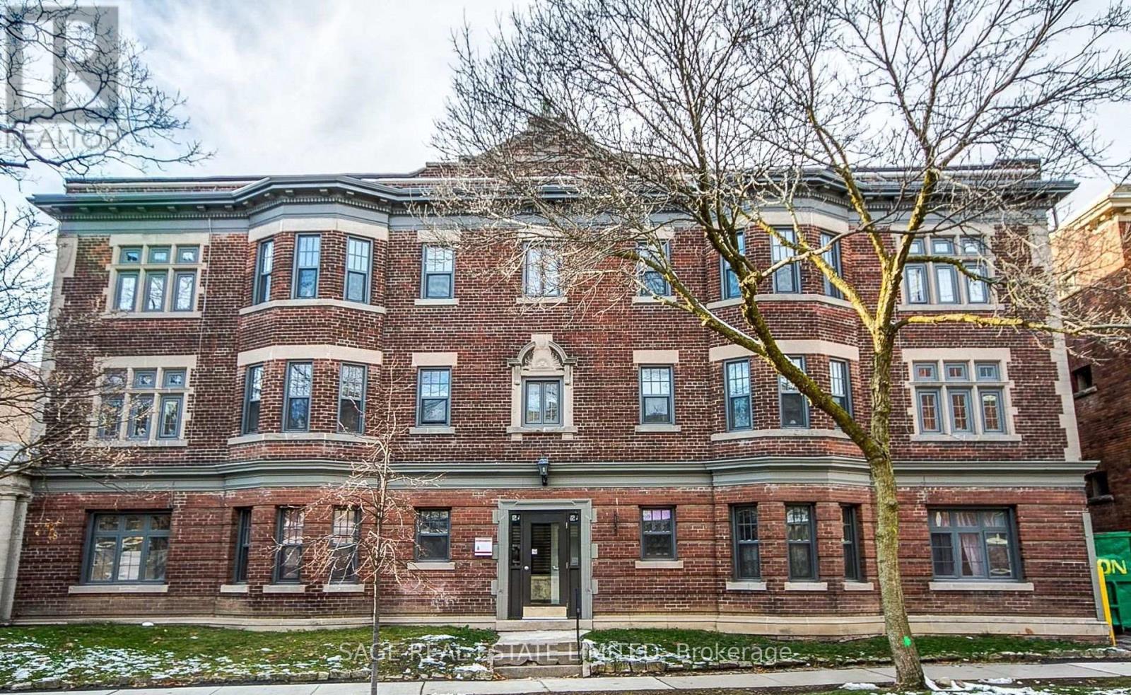 A red brick building with a tree in front.