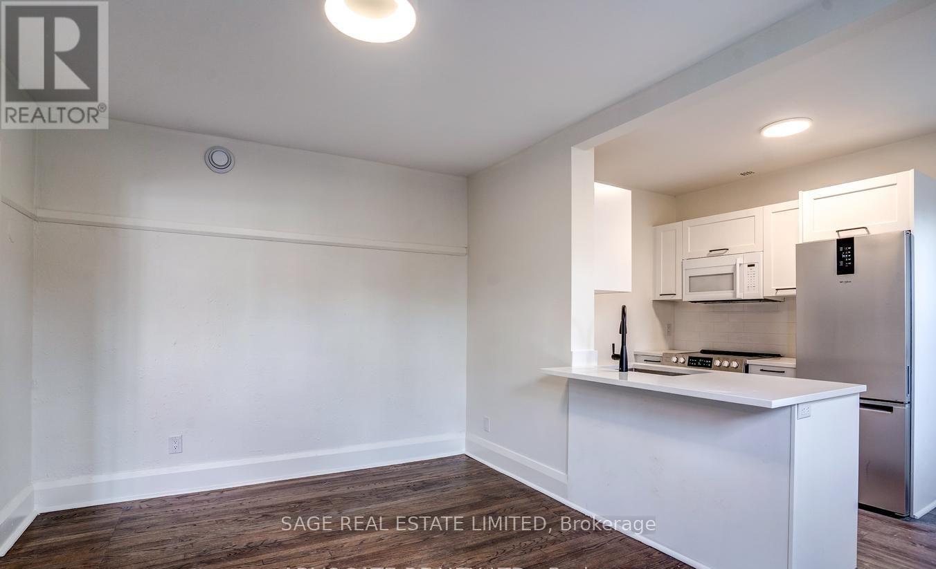 A white kitchen with a refrigerator, microwave, and oven.