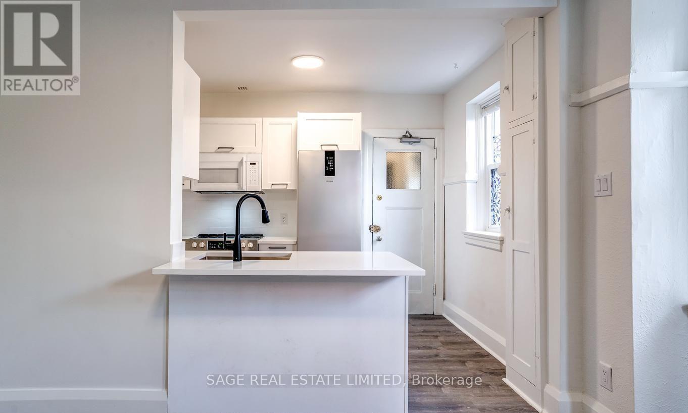A white kitchen with a sink and a refrigerator.