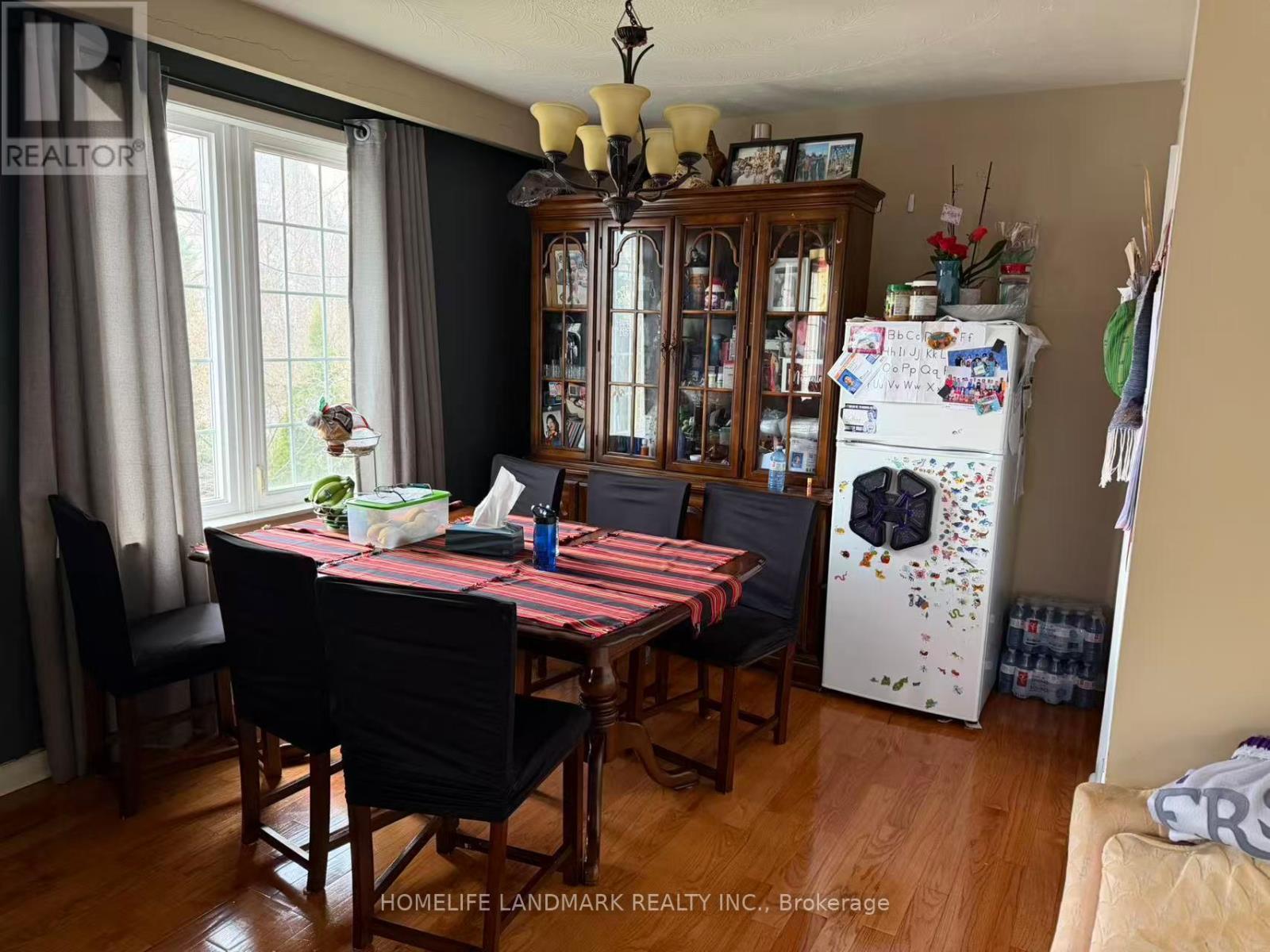 A dining room with a table and chairs and a refrigerator with magnets on it.