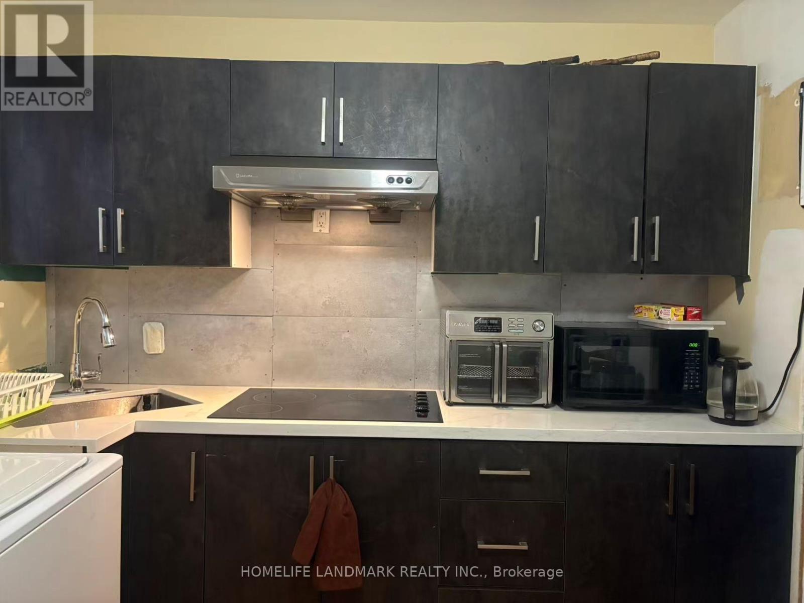 A kitchen with black cabinets and a white dishwasher.