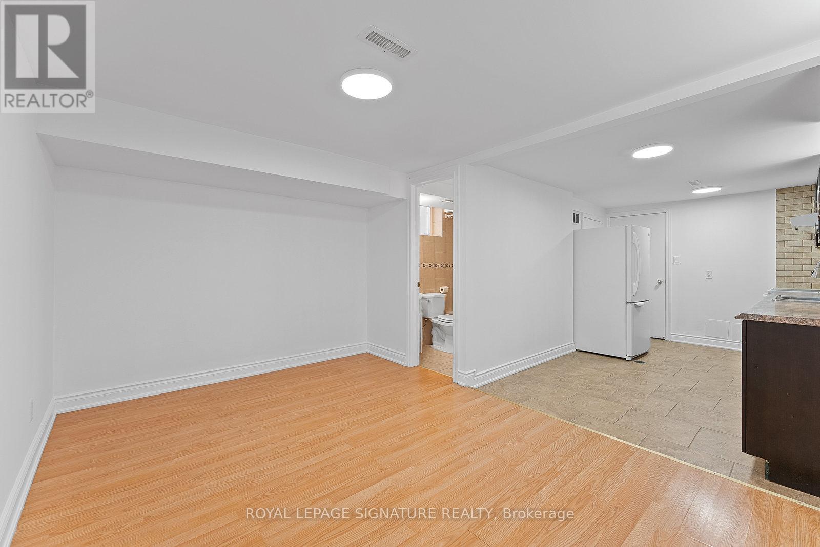 A spacious room with wooden flooring and white walls.