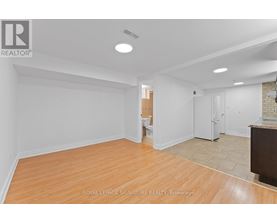 A spacious room with wooden flooring and white walls.
