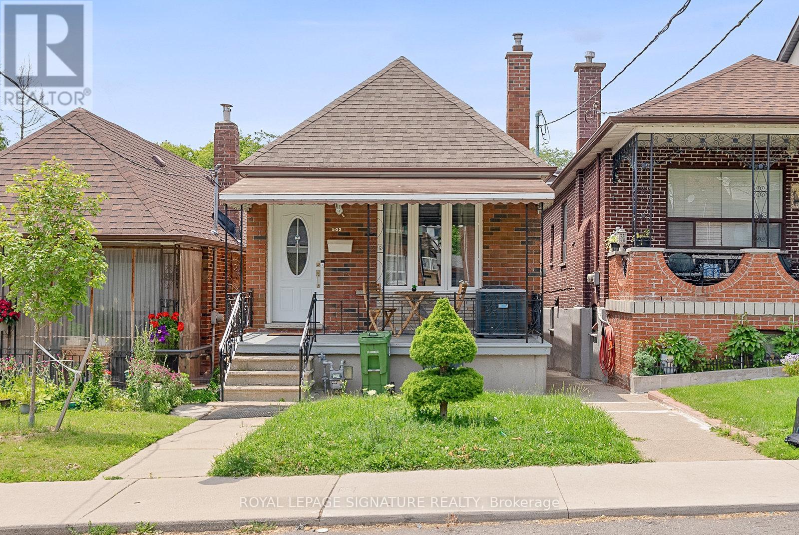A small house with a front porch and a green bush.