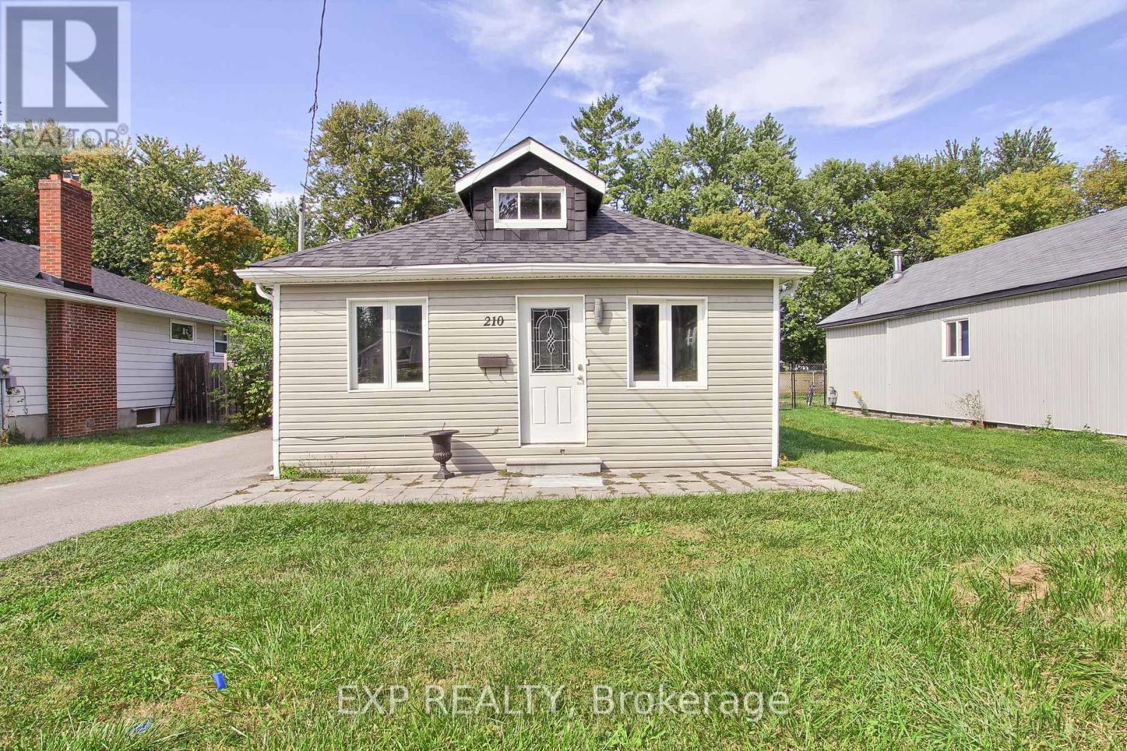 A small house with a porch and a sign that says EXP REALTY Brokerage.