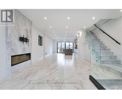 A spacious hallway with marble floors and a staircase.