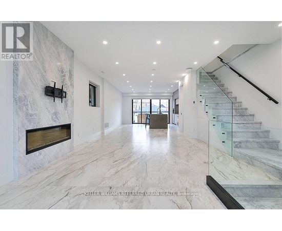 A spacious hallway with marble floors and a staircase.