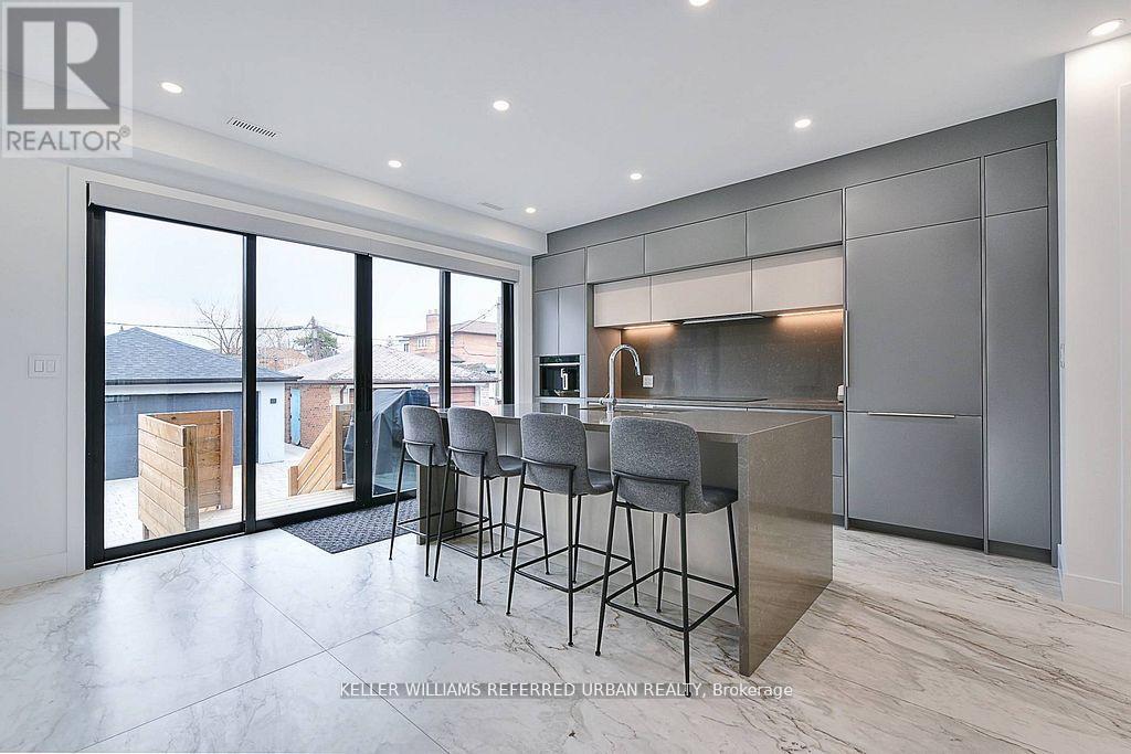 A modern kitchen with a bar area and a view of the outdoors.