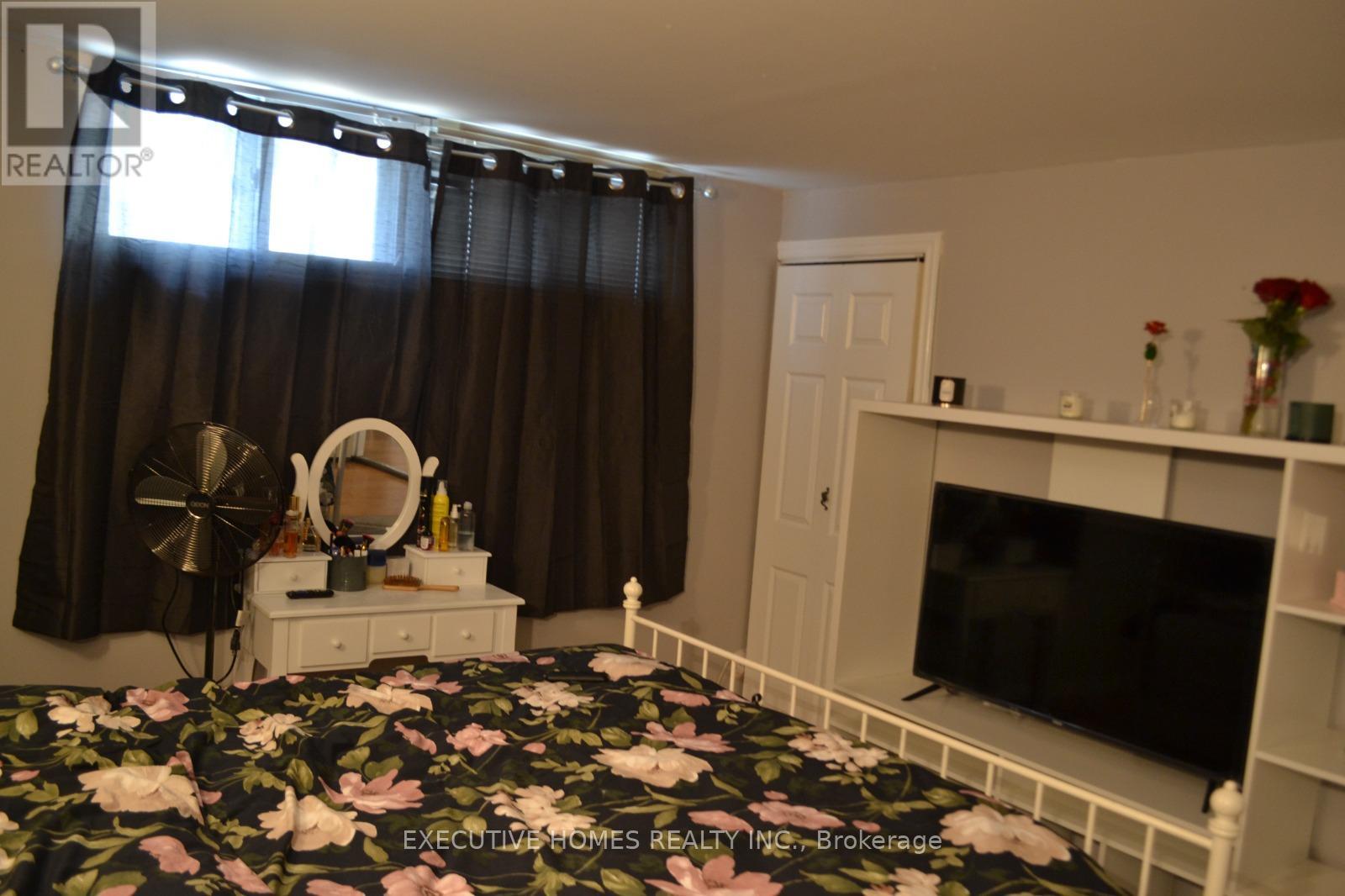 A bedroom with a floral bedspread and a television on a stand.
