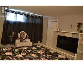 A bedroom with a floral bedspread and a television on a stand.