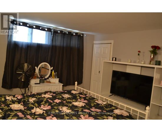 A bedroom with a floral bedspread and a television on a stand.