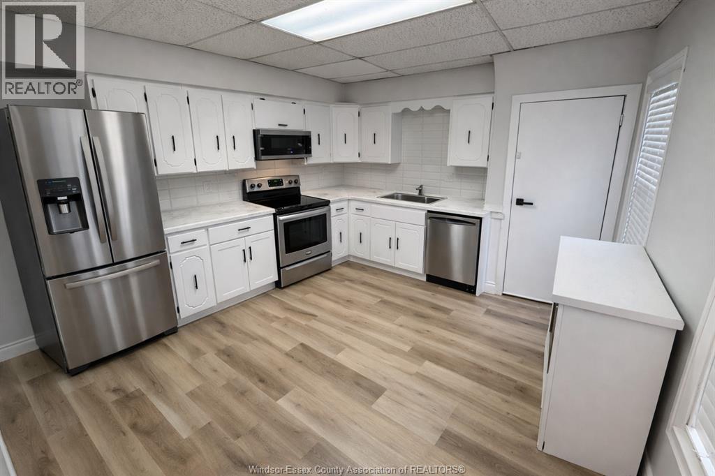 A kitchen with white cabinets and a wooden floor.