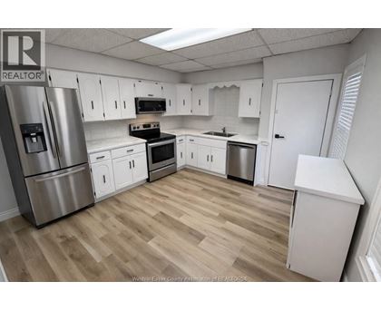 A kitchen with white cabinets and a wooden floor.