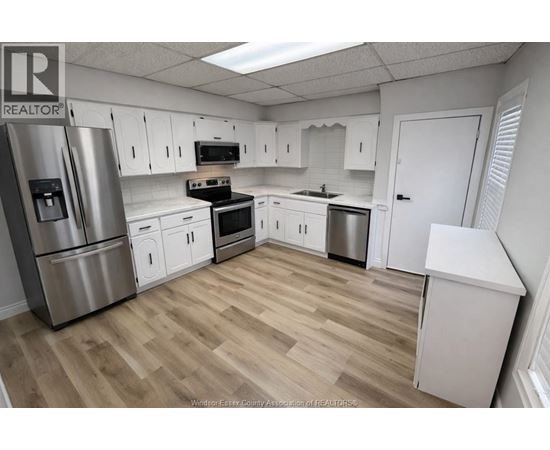 A kitchen with white cabinets and a wooden floor.