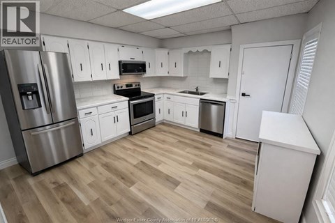 A kitchen with white cabinets and a wooden floor.