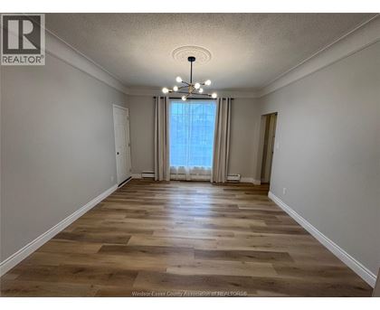 A room with wooden flooring and a large window with curtains.