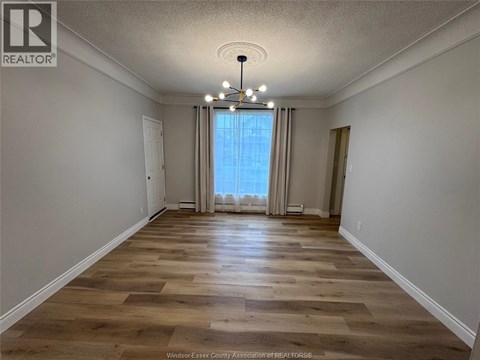 A room with wooden flooring and a large window with curtains.
