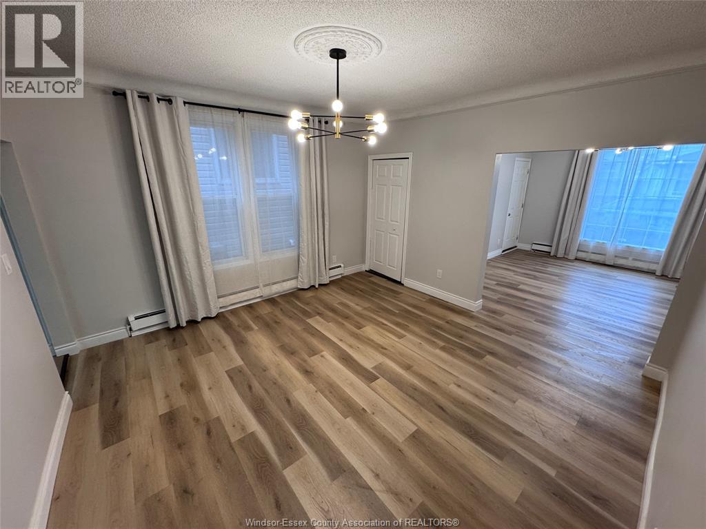 A room with wooden flooring and a chandelier.